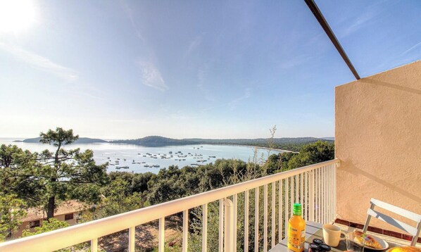 Ein Balkon mit Blick auf ein Gewässer, Boote und entfernte Küste.
