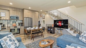 Un espacio de estar moderno con cocina, comedor y una escalera que sube a una zona superior.