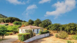 Una piccola casa con tetto in tegole, immersa nel verde e circondata da alberi.