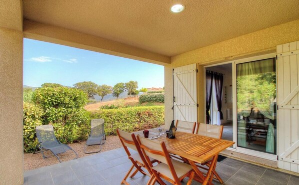 A covered patio with a table and chairs, a view of the countryside, and a sliding glass door. - The Orange Tree - SOLLACARO (SOLLACARO)
