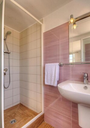 Ein Badezimmer mit Dusche, Waschbecken und Spiegel.