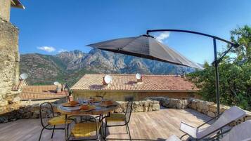 Une terrasse avec une table, des chaises et un grand parasol.