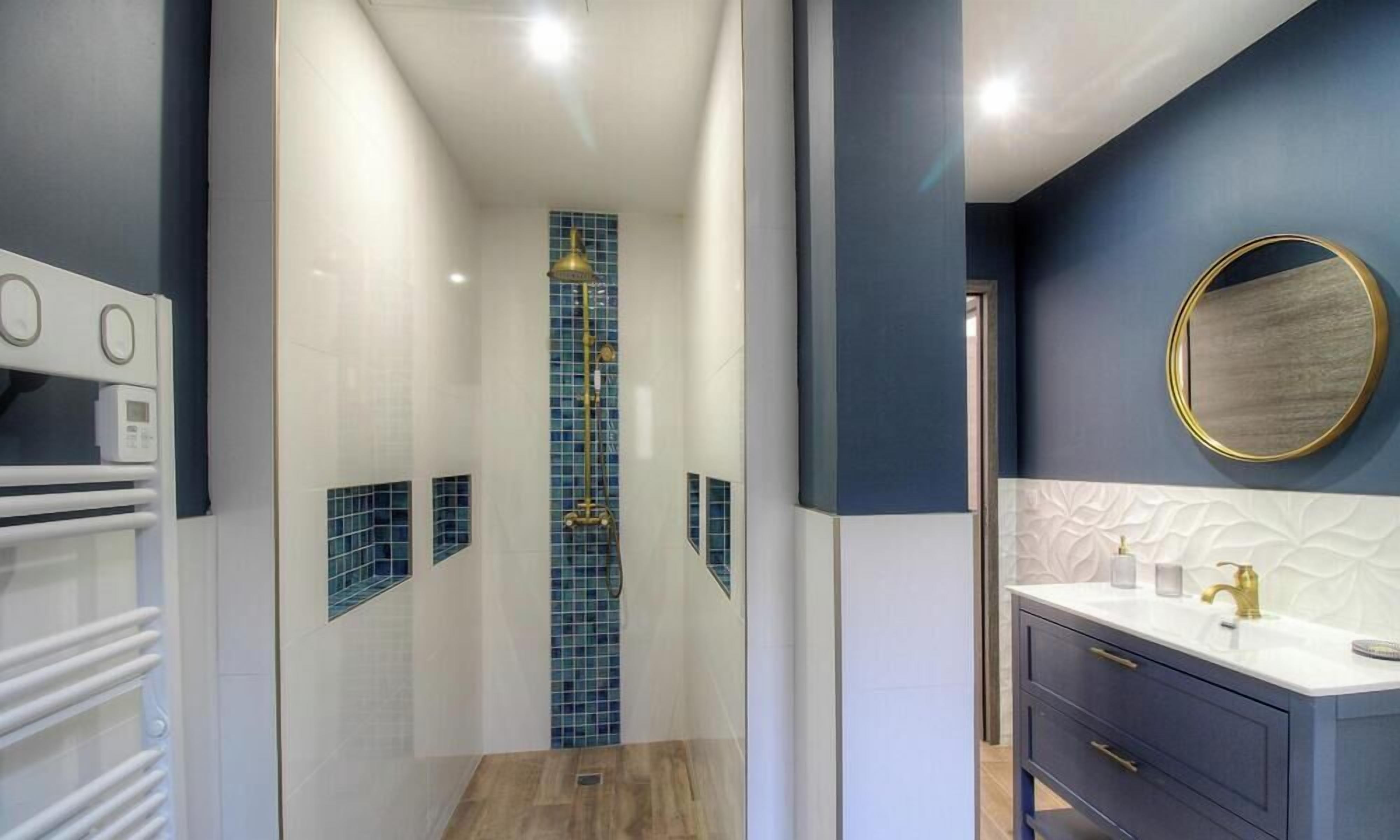 Une salle de bain moderne équipée d’une douche, d’un meuble-lavabo et d’un miroir.