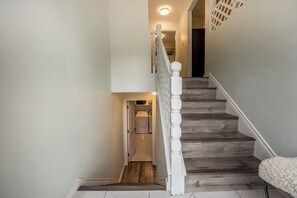A staircase with a wooden finish, a white handrail, and a white cushioned bench at the bottom. - Charming Escape  and cozy  place near everything (Surrey)