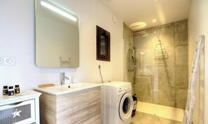 Ein modernes Badezimmer mit Waschbecken, Spiegel und einer Duschkabine.
