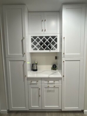 A kitchen with white cabinets, a marble countertop, and a wine rack. - Welcome to our Cozy Oasis. (Jacksonville)