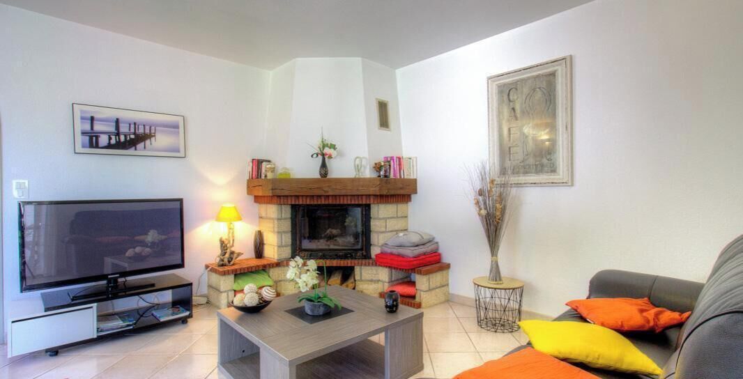 Ein Wohnzimmer mit Kamin, Fernseher, Couchtisch und Sofa.