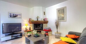 Ein Wohnzimmer mit Kamin, Fernseher, Couchtisch und Sofa.