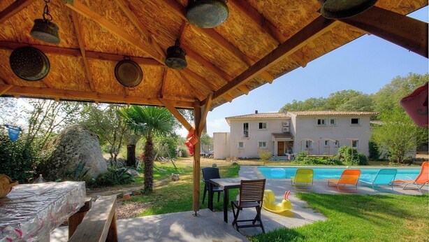 A covered outdoor area with a pool, a table, chairs, and a building in the background. - POVO - PORTO VECCHIO (PORTO VECCHIO)