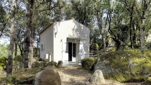 A small, white building with a door and windows, surrounded by trees and rocks. - POVO - PORTO VECCHIO (PORTO VECCHIO)