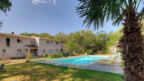 A pool with a clear blue water surface, a palm tree, and a building with a tiled roof. - POVO - PORTO VECCHIO (PORTO VECCHIO)