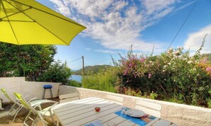 Eine Terrasse im Freien mit Tisch, Stühlen und einem gelben Sonnenschirm.