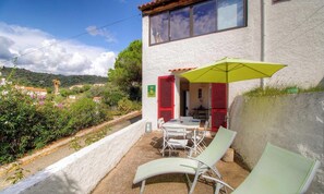 Ein Gebäude mit einer Terrasse, auf der sich ein Tisch, Stühle und ein gelber Sonnenschirm befinden.