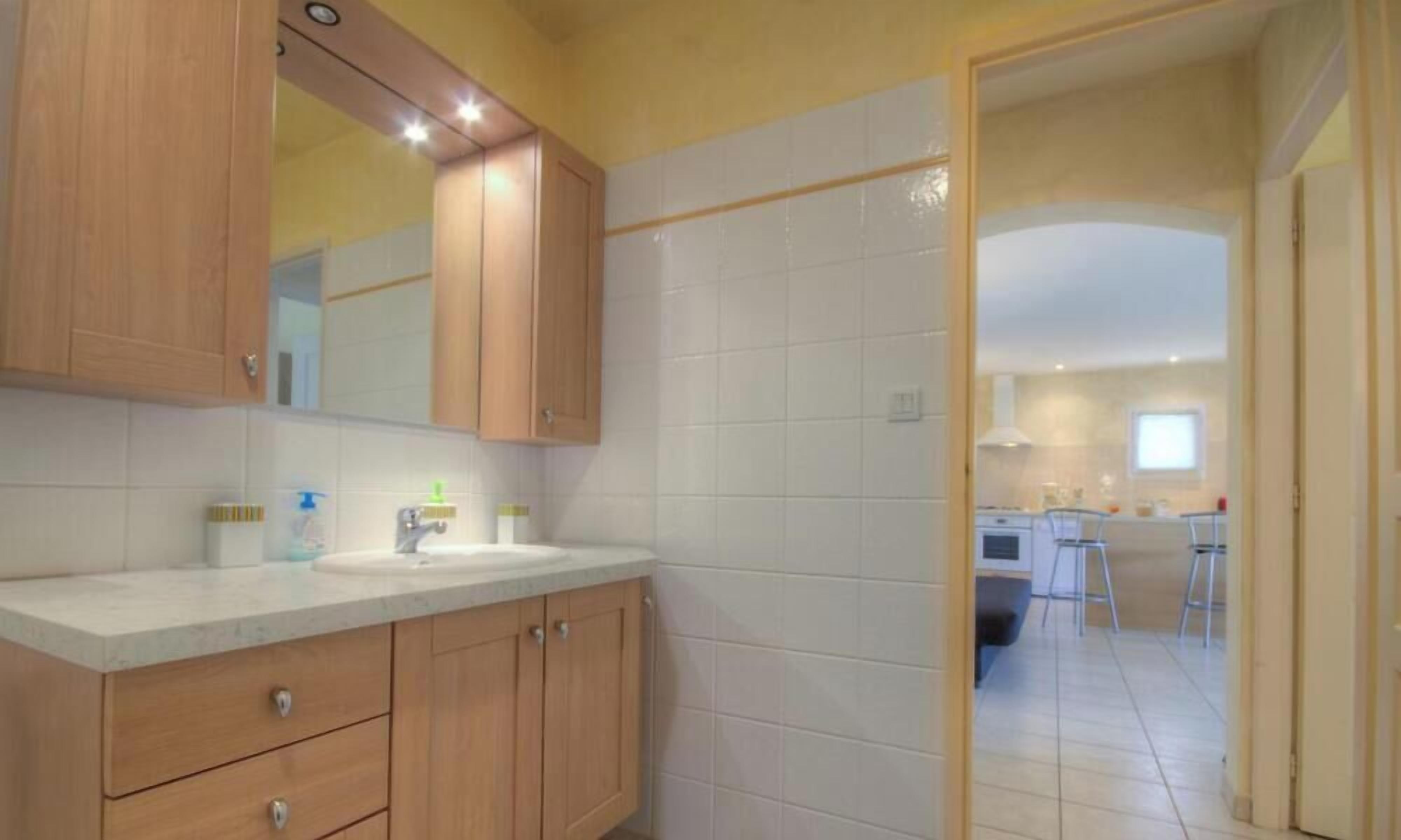 A bathroom with wooden cabinets, a sink, and a mirror.