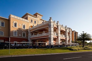 Ein mehrstöckiges Hotel mit einer zentralen Atriumhalle, Balkonen und einem Parkplatz.