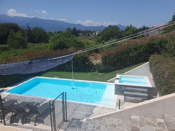 A swimming pool with a view of mountains, surrounded by greenery and a stone pathway. - L'Emera 1 - GHISONACCIA (GHISONACCIA)