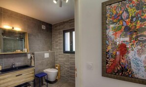 A bathroom with a modern sink, toilet, and a large framed artwork on the wall. - Santa Maria - SISCO - Gîte (SISCO)