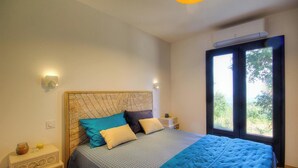 Une chambre à coucher comprenant un lit, des tables de chevet, une fenêtre et un climatiseur fixé au mur.