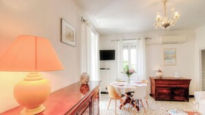 A dining area with a table set for two, a wooden cabinet, and a television mounted on the wall. - Le 22401 - PETRETO BICCHISANO (PETRETO BICCHISANO)