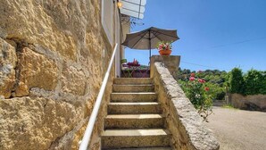 A stone staircase leading to a terrace with a table and chairs, a potted plant, and a clear blue sky. - Le 22401 - PETRETO BICCHISANO (PETRETO BICCHISANO)