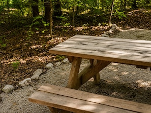 Una mesa de picnic de madera con bancos en un área boscosa.