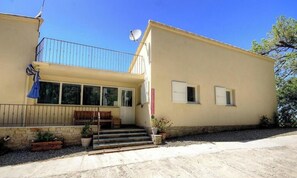 Ein zweistöckiges Gebäude mit Balkon, Satellitenschüssel und einer kleinen Veranda mit Stufen zum Eingang.