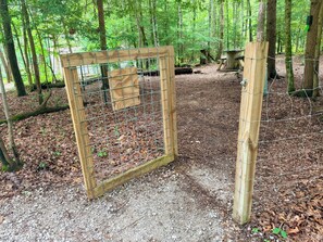 A wooden fence in a forested area with a gravel path.