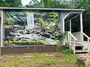 A wooden structure with a waterfall mural, a 'Welcome Campers!' sign, and a 'Private Property No Trespassing' sign.