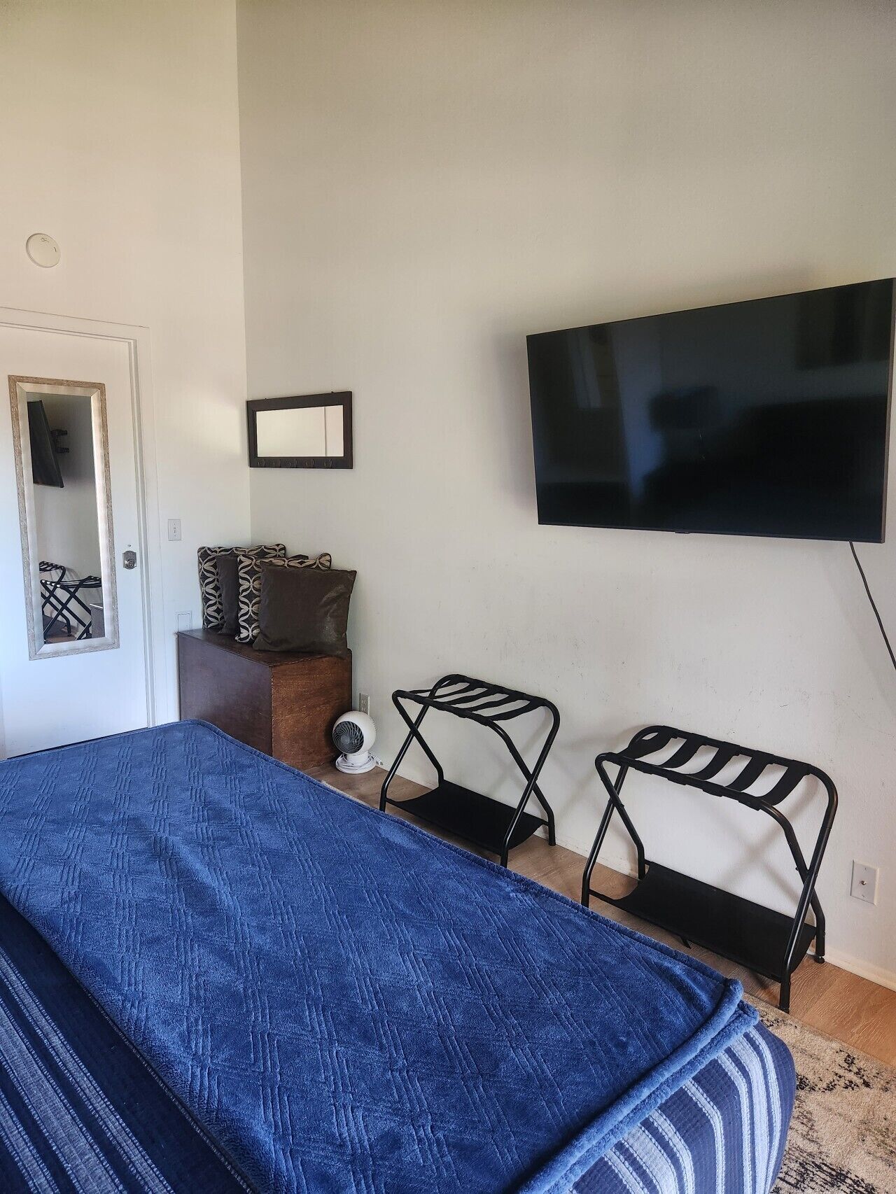 A bedroom with a bed, a TV, a mirror, and a small table.