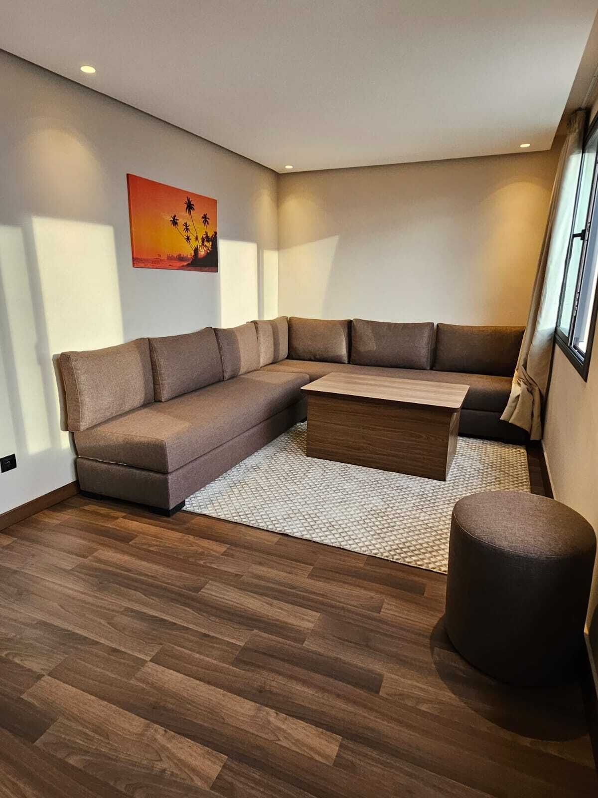 A modern living room with a sectional sofa, a coffee table, and a round ottoman.