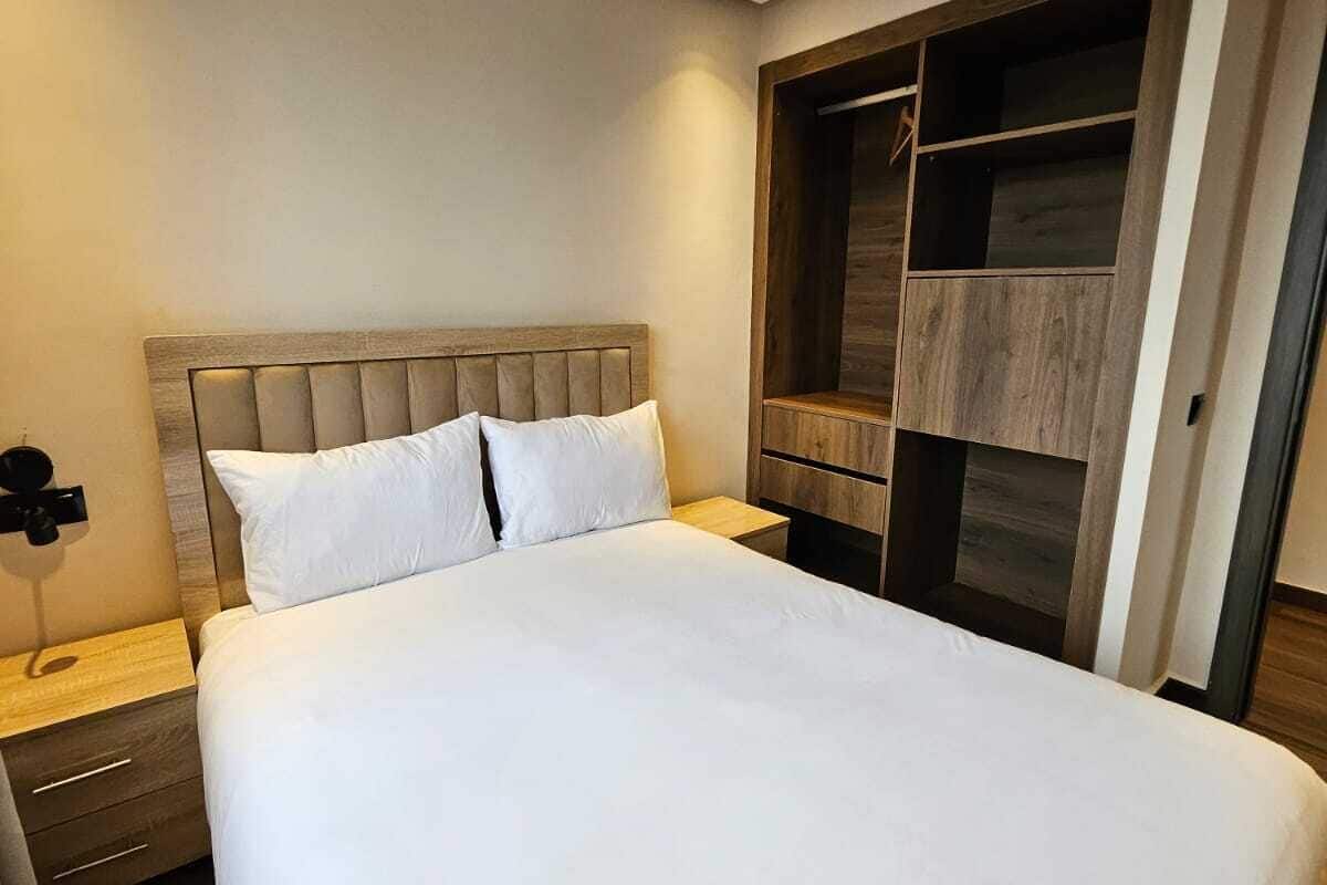 A bedroom with a large bed, wooden headboard, bedside tables, and a built-in wardrobe.