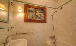 Ein Badezimmer mit Waschbecken, Spiegel, Dusche und einem gerahmten Bild an der Wand.