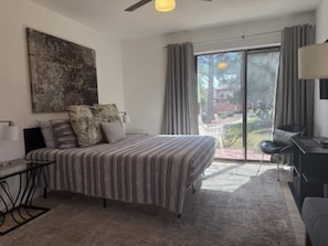 A bedroom with a bed, a desk, a chair, a ceiling fan, and a view through a sliding glass door. - Sedona 3/2 Condo Pool-HotTub-Tennis-Pickleball (Sedona)