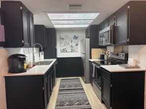 A compact kitchen with dark cabinetry, a microwave, a stove, and a coffee maker. - Sedona 3/2 Condo Pool - Hot Tubs - Tennis-Pickleball (Sedona)