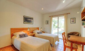 Ein Hotelzimmer mit zwei Betten, einem Holzkopfende, einem Schreibtisch und einem Stuhl.