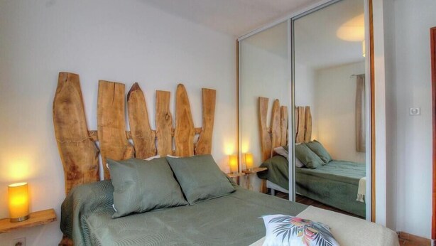 A bedroom with a bed, two bedside lamps, a large mirror, and a wooden headboard. - La Cardiccia - BALOGNA (BALOGNA)
