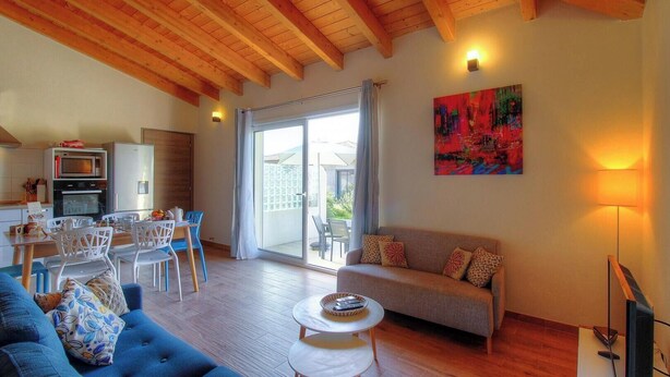 A living room with a sofa, coffee table, and dining area with chairs. There is a kitchen with a microwave and oven, and a balcony with a table and chairs. - Villa Marie - FIGARI (FIGARI)