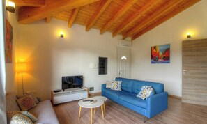 Ein Wohnzimmer mit Fernseher, Sofa, Couchtisch und einem Gemälde an der Wand.