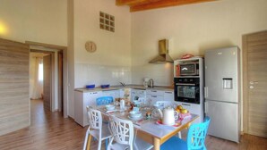 A compact kitchen with white appliances, a dining table set with chairs, and a wooden ceiling. - Villa Marie - FIGARI (FIGARI)