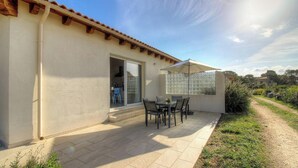 A patio with a table and chairs, a sliding glass door, and a covered area with a window. - Villa Marie - FIGARI (FIGARI)