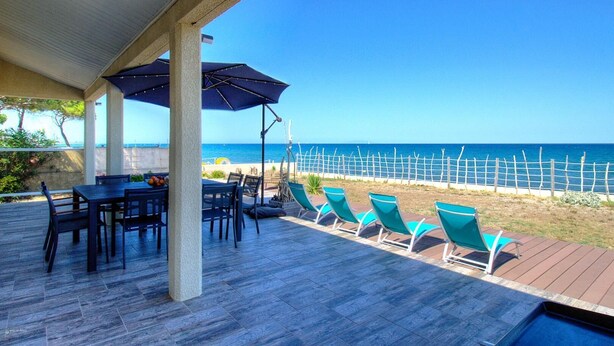 Un patio techado con una mesa y sillas, una piscina y vistas al mar.