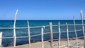 Una valla de madera con cuerdas, cielo azul despejado y mar tranquilo.