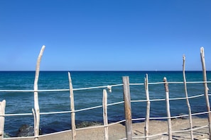 Une clôture en bois avec des cordes, un ciel bleu dégagé et une mer calme.