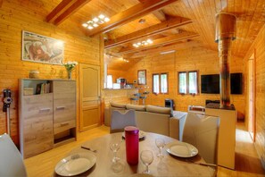 Ein gemütliches Blockhaus-Interieur mit Essbereich, Küche und einer großen Holzbalkendecke.