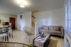 Una sala de estar con sofá, una silla, una mesa de centro y un comedor con sillas y una mesa.