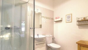 Ein Badezimmer mit Duschkabine, Waschbecken, Toilette und Holzschrank.