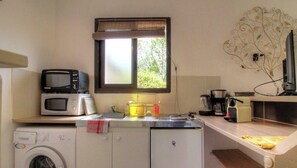 Eine kleine Küche mit Waschmaschine, Mikrowelle und Kaffeemaschine.