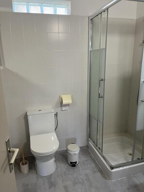 Un baño con inodoro, bidé y ducha con mampara de vidrio.