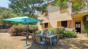 Une terrasse avec une table et des chaises, entourée de plantes et de fleurs en pot.