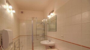 Un baño con cabina de ducha de vidrio, lavamanos y espejo.